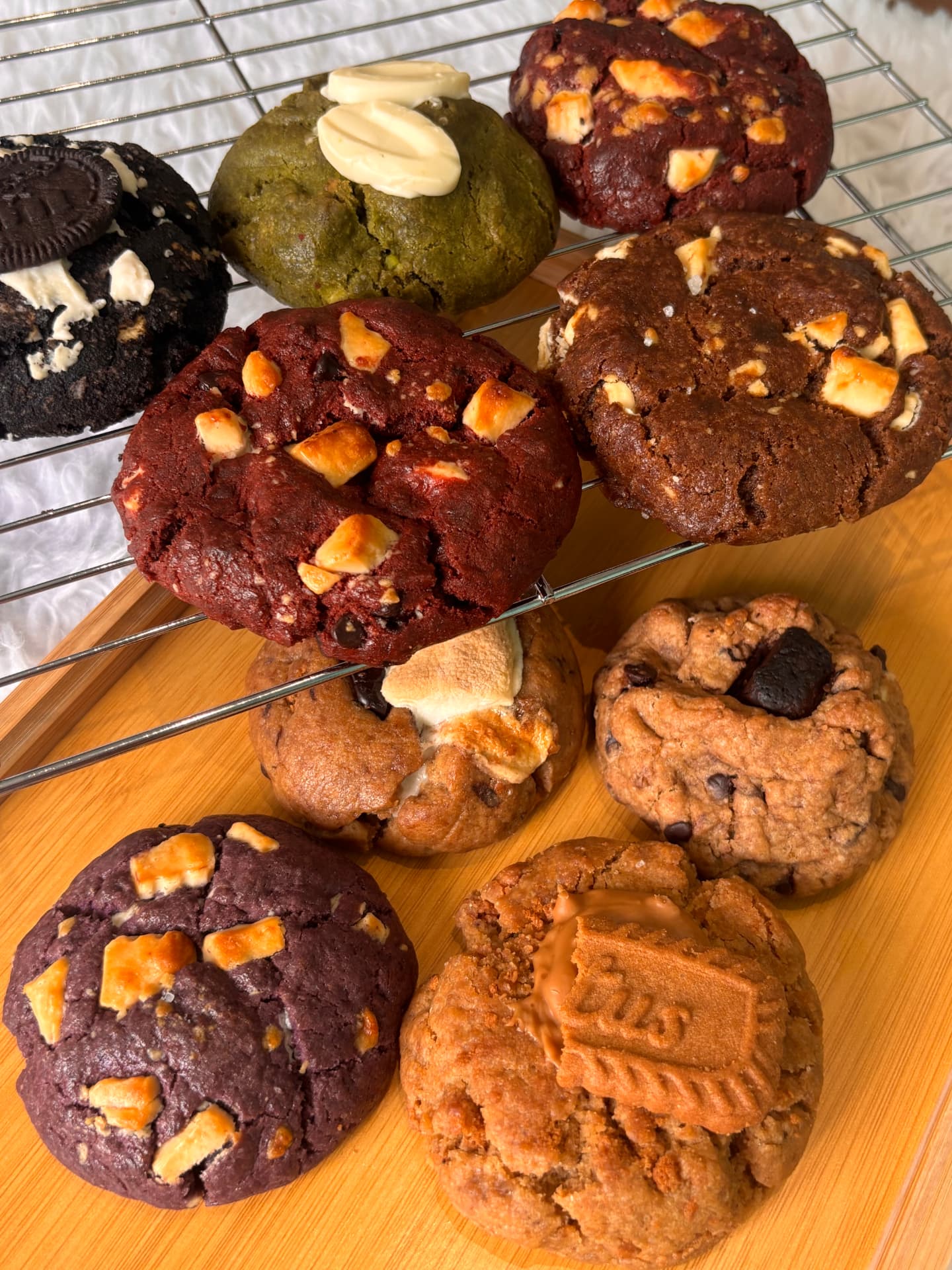 Fresh Hana Kumi cookies cooling on a rack — red velvet, matcha, ube, Biscoff and chocolate chip